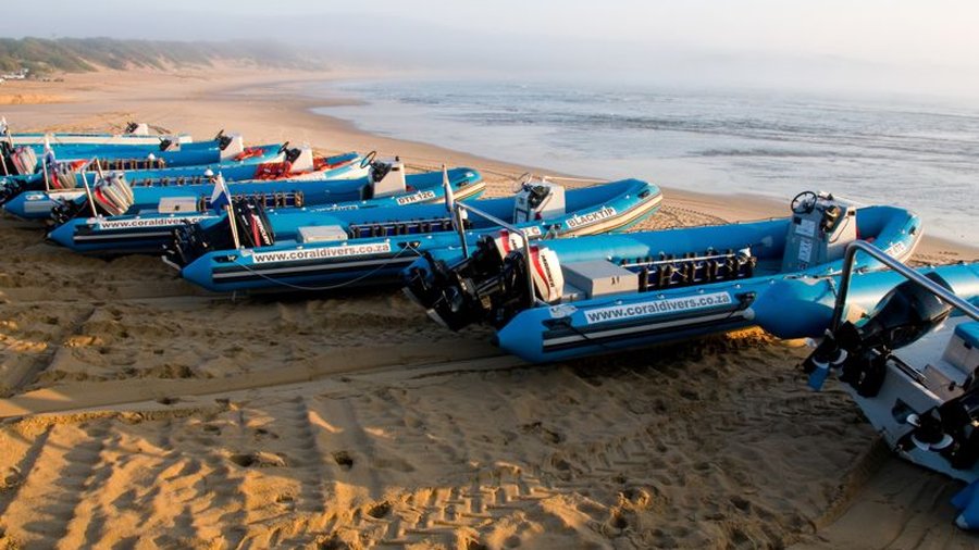 Dive boats lined up on the beach at Sodwana Bay at sunrise